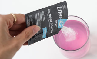 Woman pouring an Ener-C Sport electrolyte drink mix packet into her lemonade